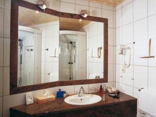 a bathroom with a sink and a large mirror at Moselstern Hotel Brixiade &Triton in Cochem