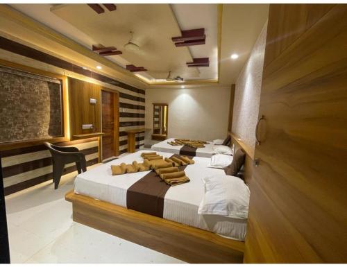 Un dormitorio con 2 camas y una silla. en Hotel Sukhnath, Somnath, en Somnath