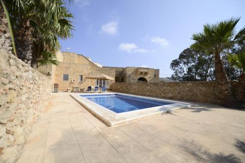 una piscina di fronte a un muro di pietra di Karmnu Holiday Farmhouse a Għasri