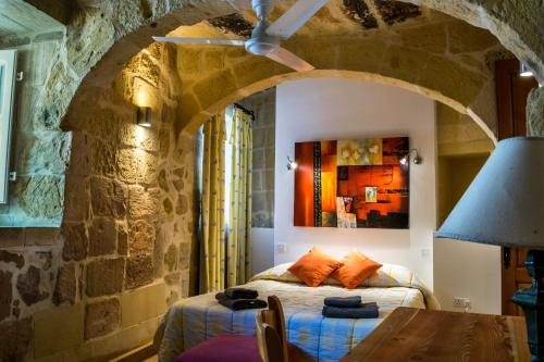 een slaapkamer met een bed in een stenen muur bij Karmnu Holiday Farmhouse in Għasri