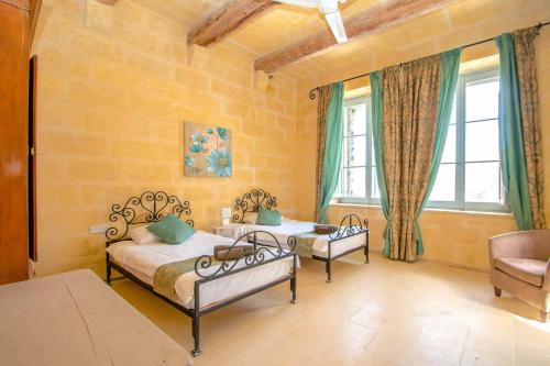 two beds in a room with two windows at Ghar Ilma IV Holiday Home in Santa Luċija