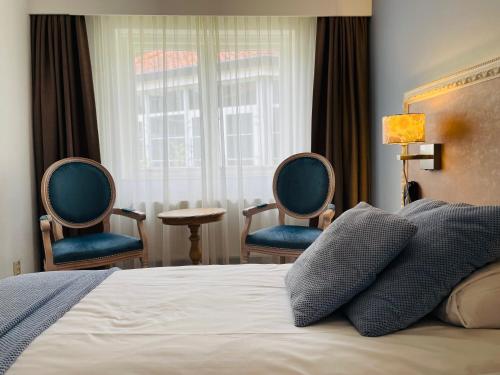 um quarto com 2 cadeiras, uma cama e uma janela em Landgoedhotel Villa Vennendal em Nunspeet