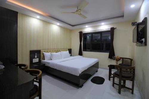 a bedroom with a bed and a television and a table at Hotel Jyoti International in Āsansol