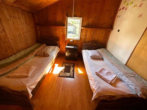 two beds in a wooden cabin with a window at Guesthouse Angelina in Ushguli