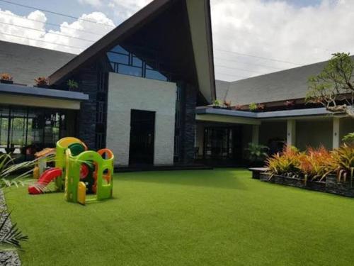 a house with a green yard with a playground at Vimalla Hills Villa Resort Exclusive Villa Puncak in Gadok 1