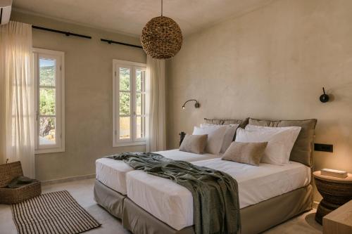 a bedroom with a large bed and two windows at Uberina - Olea Di Assos Villas in Asos
