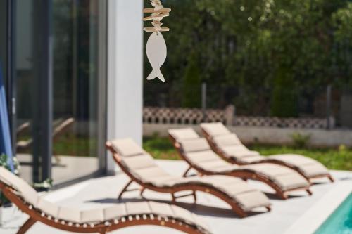 un gruppo di sedie sedute accanto a una piscina di Villa Martin Noel a Poreč (Parenzo)