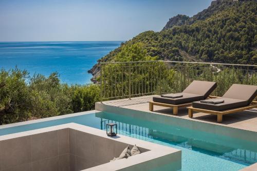 a pool with two lounge chairs and the ocean at Uberina - Olea Di Assos Villas in Asos