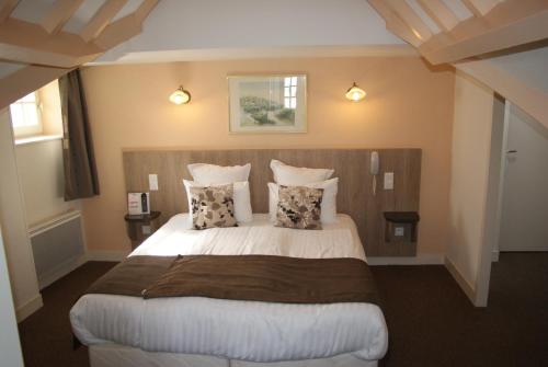 a bedroom with a large bed with two pillows at La Vieille Auberge in Le Mont Saint Michel