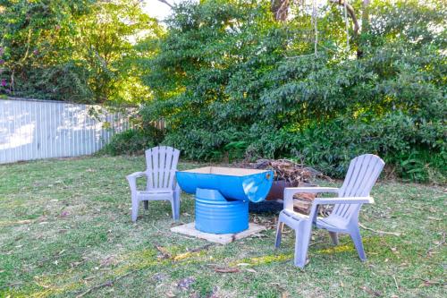 two chairs and a blue bird bath in a yard at The South Sussex Cottage in Sussex inlet