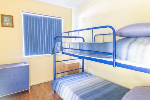 a bunk bed room with two bunk beds and a window at The South Sussex Cottage in Sussex inlet