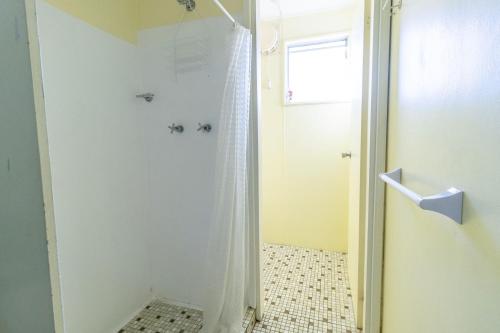 a shower with a shower curtain in a bathroom at The South Sussex Cottage in Sussex inlet
