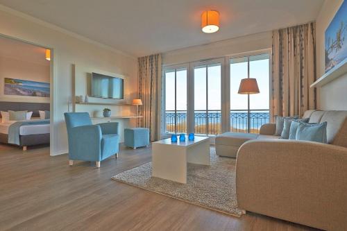 un soggiorno con divano e una camera con vista di Aparthotel Waterkant Suites - Fewos am Meer mit SPA a Börgerende-Rethwisch