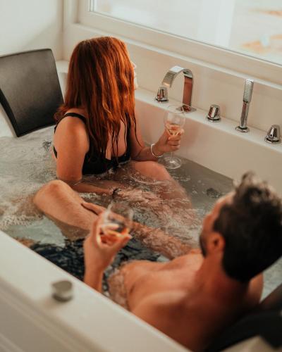 a man and woman sitting in a bath tub with wine glasses at Methe in Lizzano