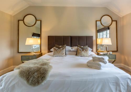 um quarto com uma grande cama branca e 2 espelhos em The Farmhouse at Marrington Estate em Chirbury