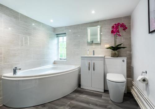 een witte badkamer met een bad en een toilet bij The Farmhouse at Marrington Estate in Chirbury