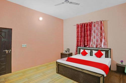 1 dormitorio con 1 cama con almohadas rojas en Flagship Hotel Status en Bareilly
