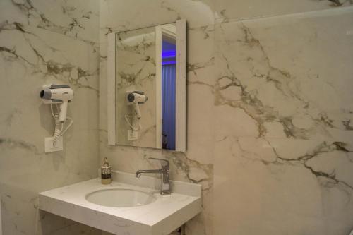 ein Bad mit einem Waschbecken und einem Spiegel in der Unterkunft Red Hill Hotel in Tirana