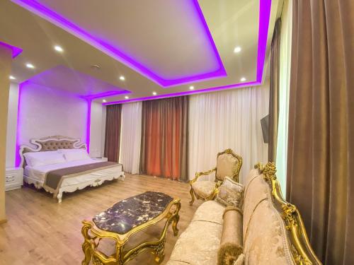 ein Schlafzimmer mit einem Bett und einem Sofa und lila Beleuchtung in der Unterkunft Red Hill Hotel in Tirana
