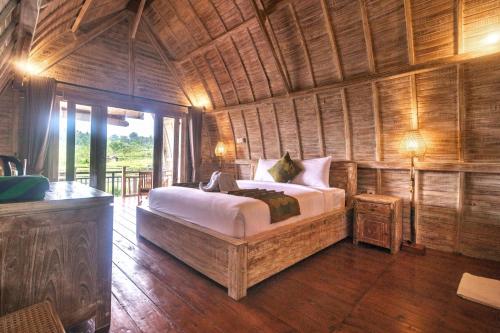 um quarto com uma cama num quarto com paredes de madeira em AlamGangga Villas Tirta Gangga em Tirtagangga