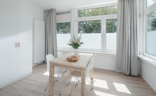 uma sala de jantar com mesa, cadeiras e janelas em Strandloft Eins Norderney em Norderney