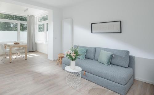 uma sala de estar com um sofá azul e uma mesa em Strandloft Eins Norderney em Norderney