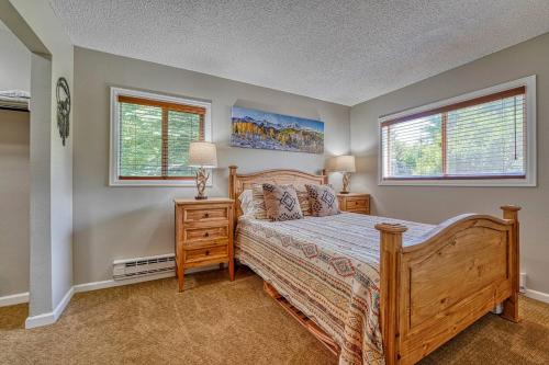 a bedroom with a wooden bed and two windows at Riverfront family-friendly condo in Avon