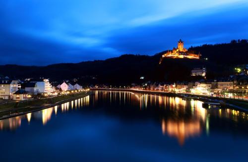 a city lit up at night with a river at Moselstern Hotel Brixiade &Triton in Cochem