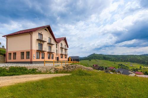 un gran edificio en una colina con un campo verde en Шепіт Лісу en Bukovel