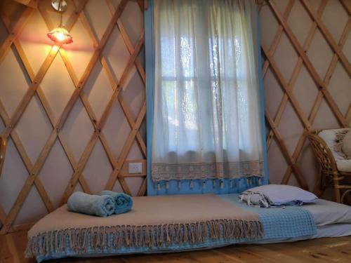 a bed in a room with a curtain and a window at Love Frequency - יורט קסום במתת in Mattat