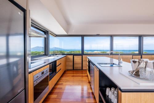 a kitchen with large windows and a counter with sinks at Elements - Freycinet Holiday Houses in Dolphin Sands