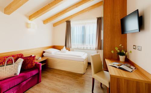 a hotel room with a bed and a couch at Astor Hotel in Schenna