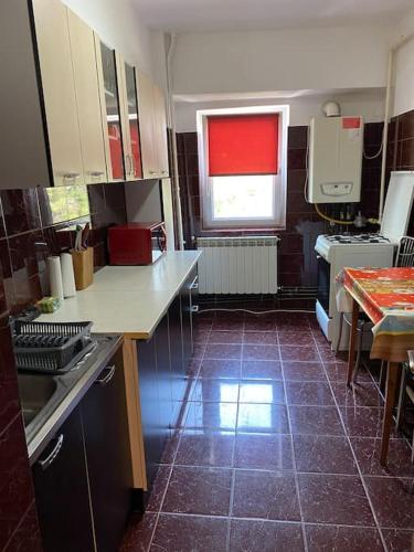 a kitchen with a red window and a tile floor at Sunshine Faleza Nord in Constanţa