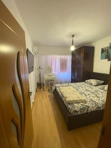 a bedroom with a bed and a table and a window at Sunshine Faleza Nord in Constanţa