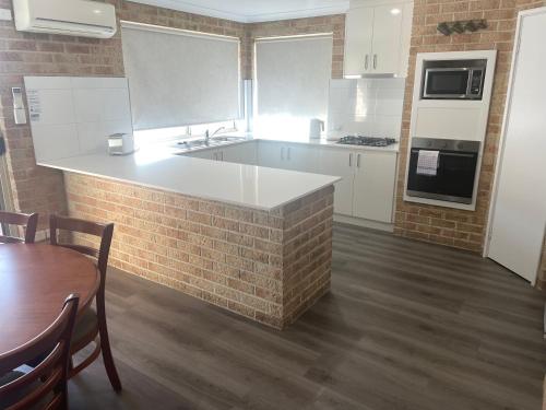 a kitchen with white appliances and a brick wall at Frangipani in Albany