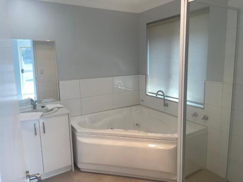 a white bathroom with a tub and a sink at Frangipani in Albany
