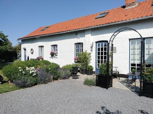 een wit huis met een boog ervoor bij La tiote glaine in Cappelle-en-Pévèle