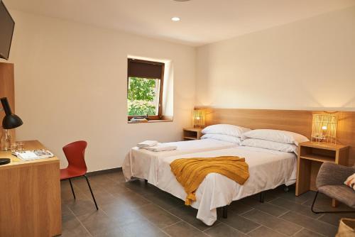 1 dormitorio con cama, escritorio y ventana en Hotel Casa Palacio Pereros, en Cáceres