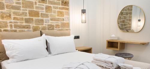 a bedroom with a white bed with a stone wall at Aurelia Luxury Apartments in Agios Ioannis Kaspaka