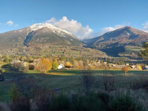 a mountain in the distance with a field and trees at Gîte confort 15 couchages, vue panoramique Montagne Hautes Alpes, Terrasses in Embrun