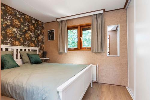 een slaapkamer met een bed en een raam bij Huize Bosrijk aan het water in Kootwijk