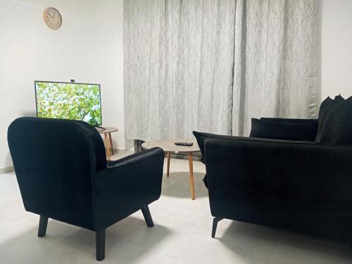 a living room with two chairs and a table at Agamim Park Residence in Ashkelon