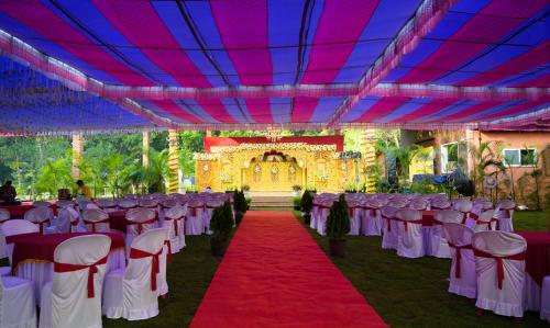 a banquet hall with white chairs and a red carpet at Kanasu The Resort - Cottages & Farm House in Udupi