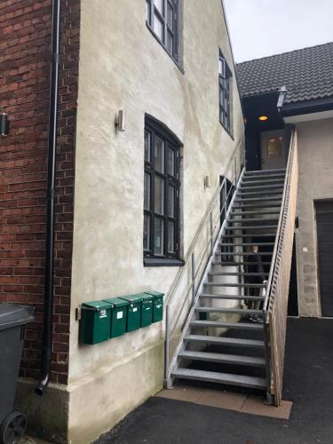 a person sitting on the stairs of a building with trash cans at Kirkegata 7 in Sarpsborg