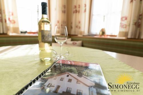 a bottle of wine and a book on a table with a wine glass at Simonegg in Schladming