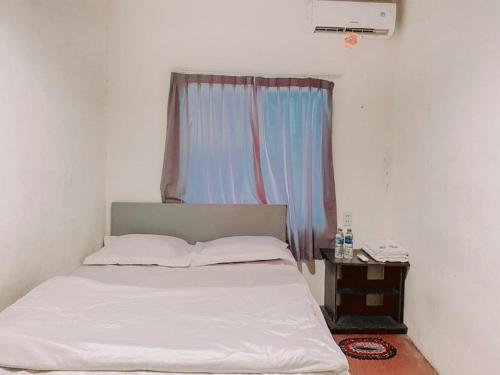 a bedroom with a white bed and a window at Penginapan Steady Mitra RedDoorz in Pematangsiantar