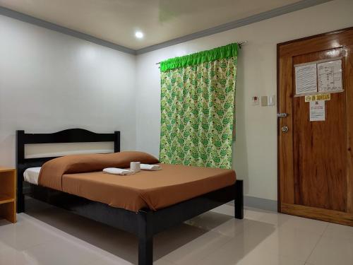 a bedroom with a bed with a green curtain and a door at El Juliana Hotel in Vigan