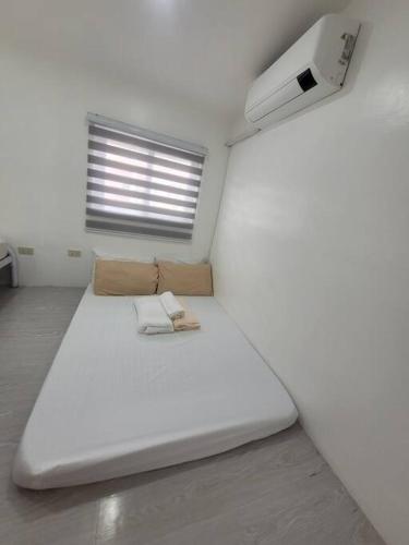 a room with a large white bed with a window at Budget friendly yet cozy staycation in Calapan