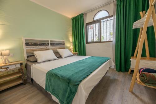 a bedroom with a bed with green curtains and a window at in front of the pool, large terrace, elegant & confortable, Wi-Fi in Costa Calma