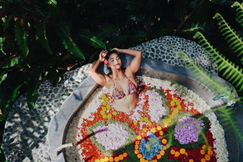 a woman laying in a bath tub filled with flowers at Maha Hills Resort by Mahaprana Experience in Lovina